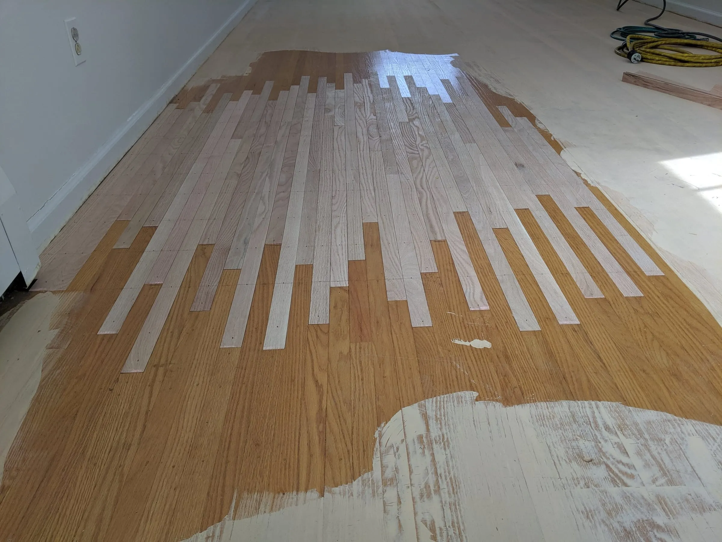 Patched oak floor partly sanded, blending new boards with the old