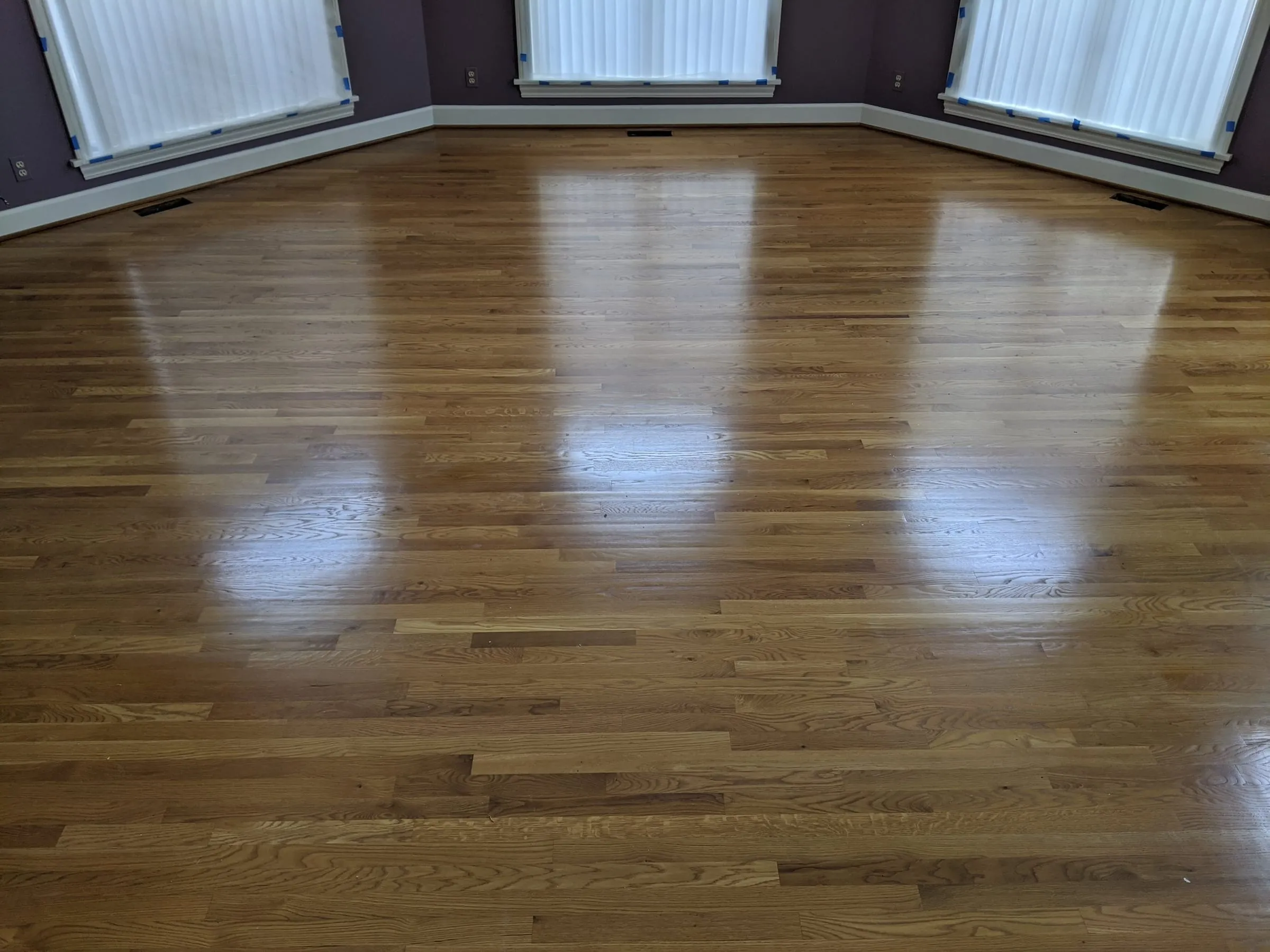 Glossy refinished oak floor in a bay-windowed room