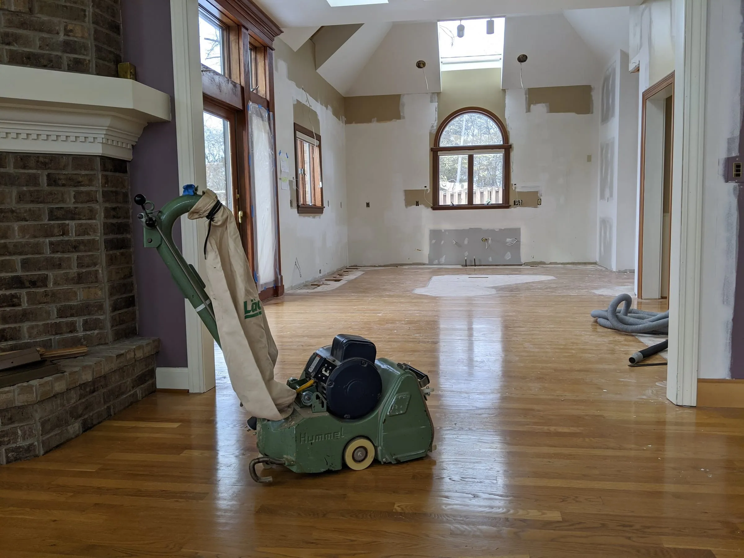 Sanding equipment beside a brick fireplace during an oak floor refinish