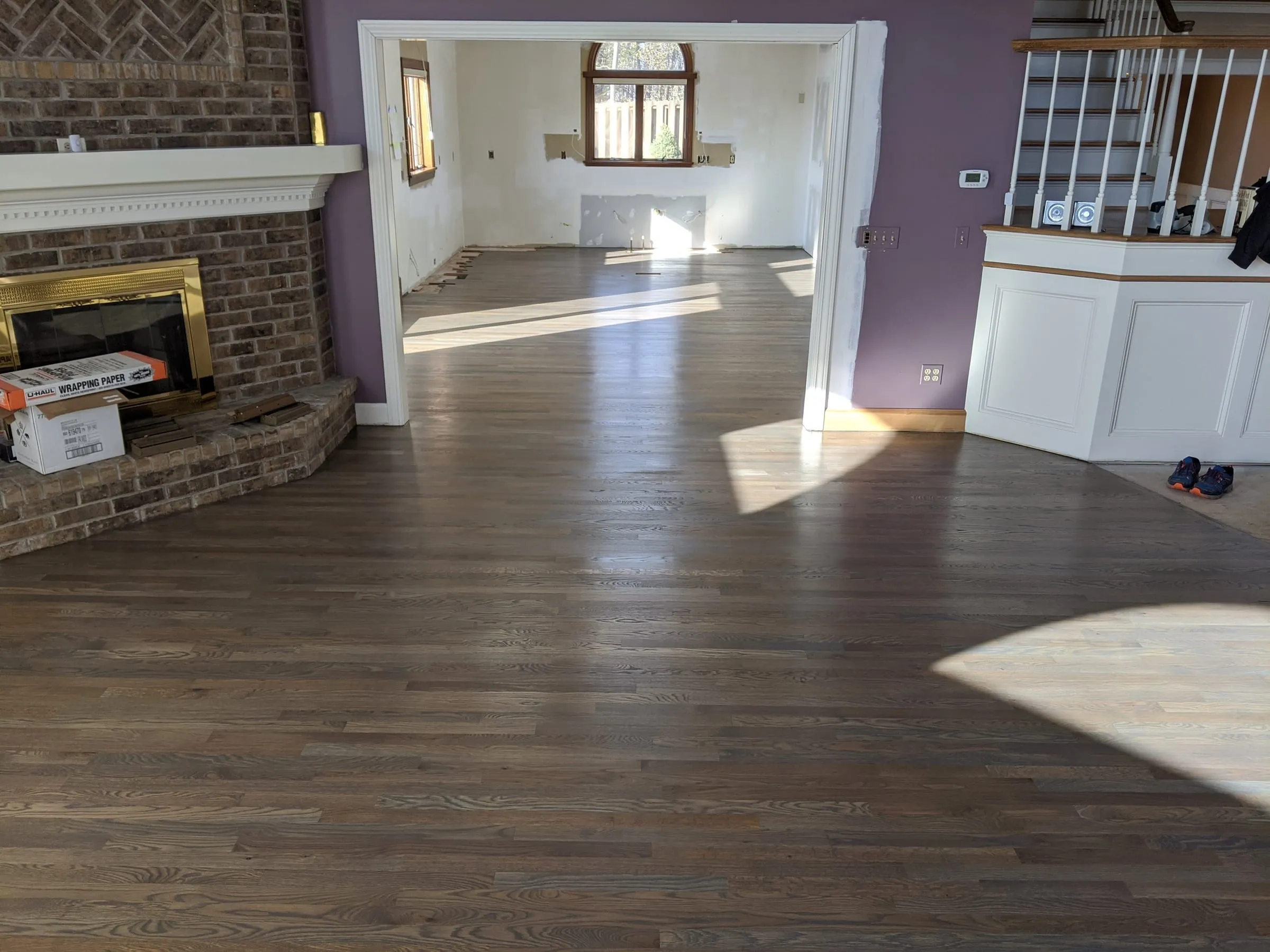 Refinished gray-brown oak floor flowing from the living room into the next room