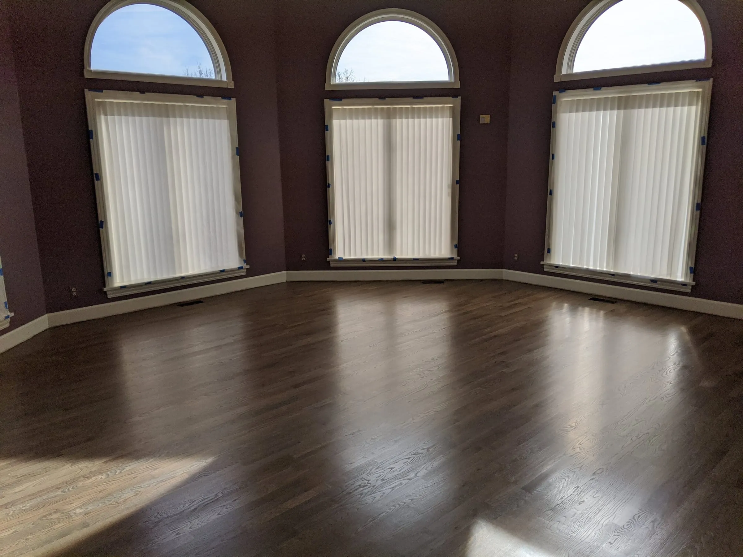 Dark refinished oak floor in a room with three arched windows