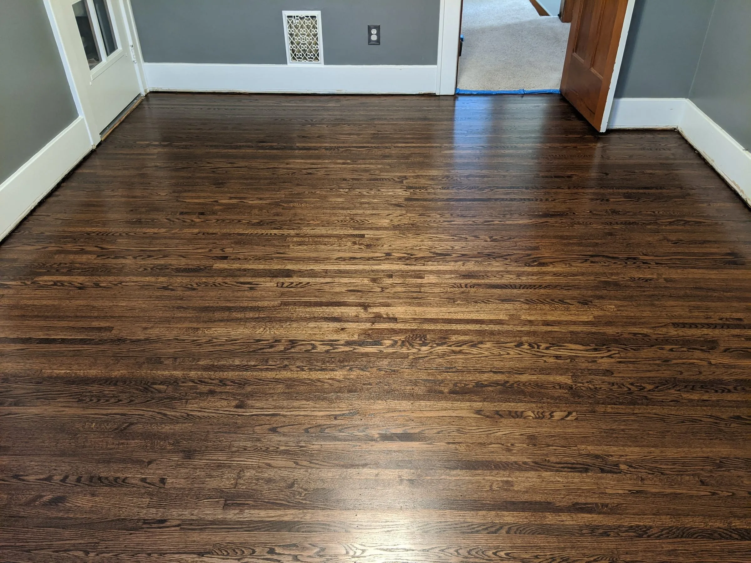 Dark walnut-stained oak floor in a bedroom with white trim
