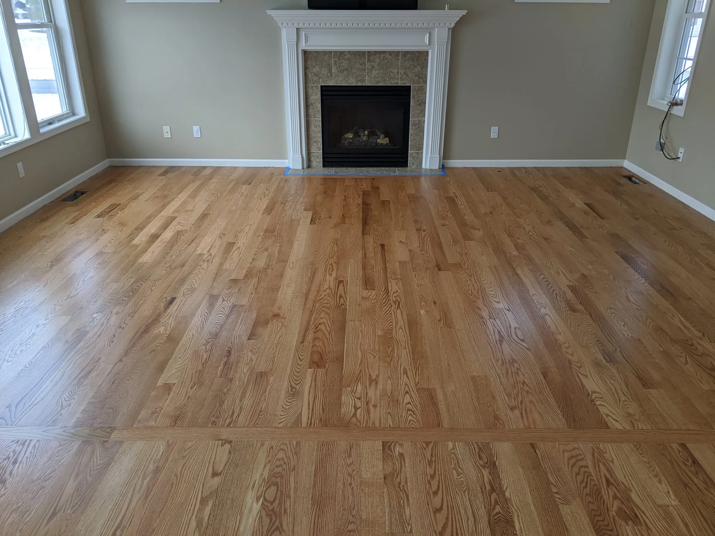 Living room oak floor finished in a natural tone in front of a fireplace