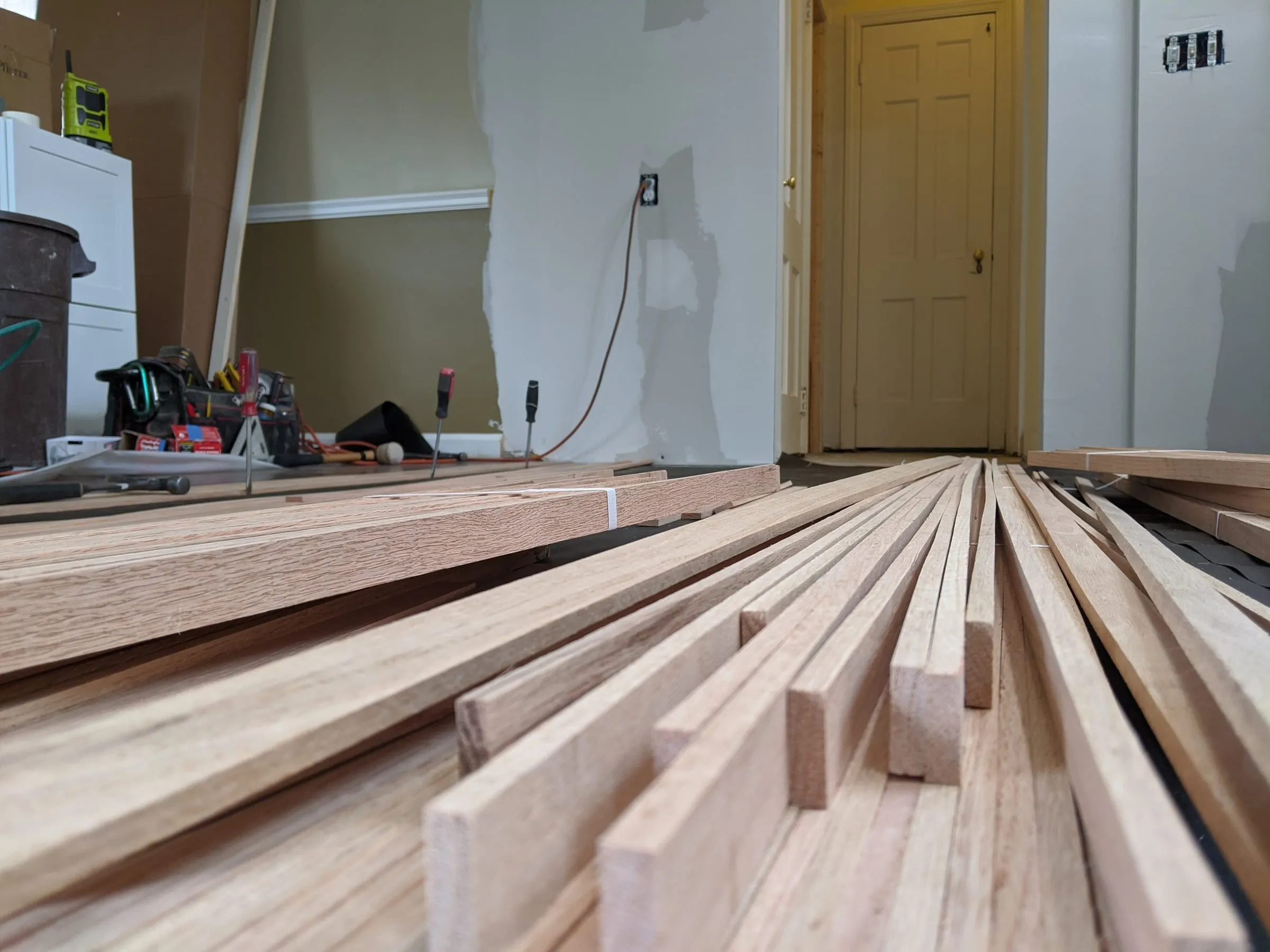 Bundles of new oak flooring strips stacked across a floor before install