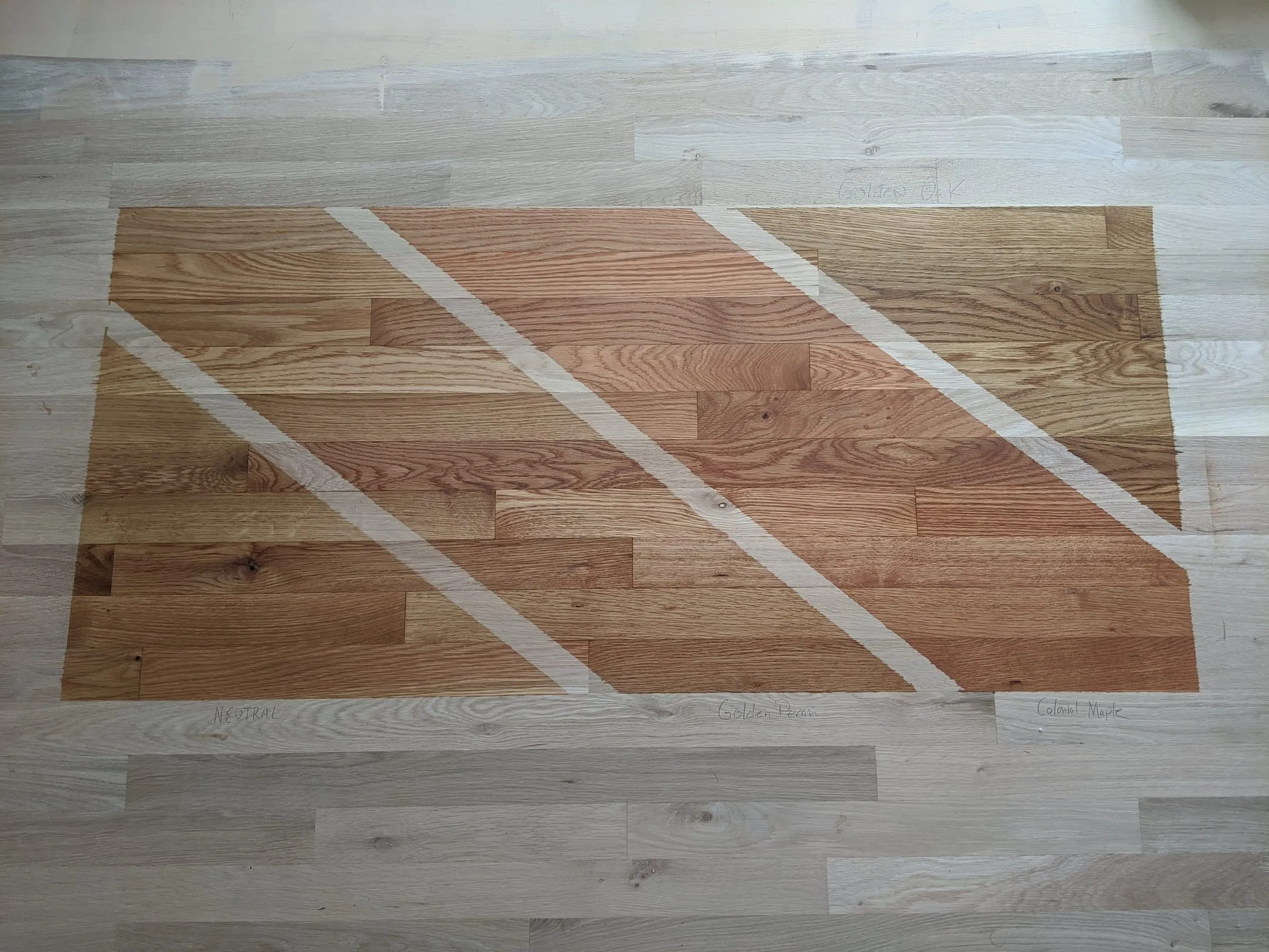 Natural oak and lighter stain test patches on a sanded floor