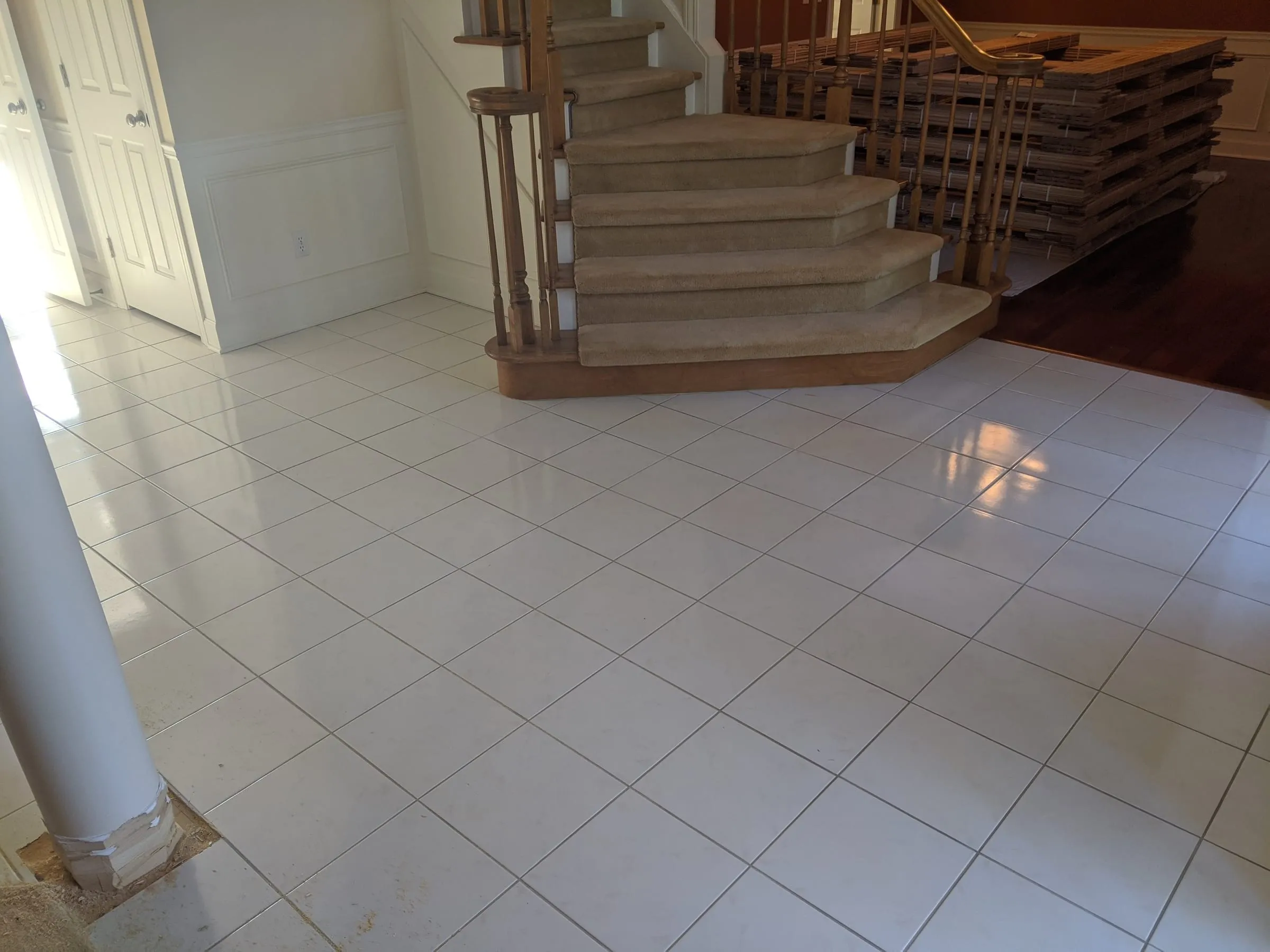 Tiled foyer with a curved staircase before wood treads are installed