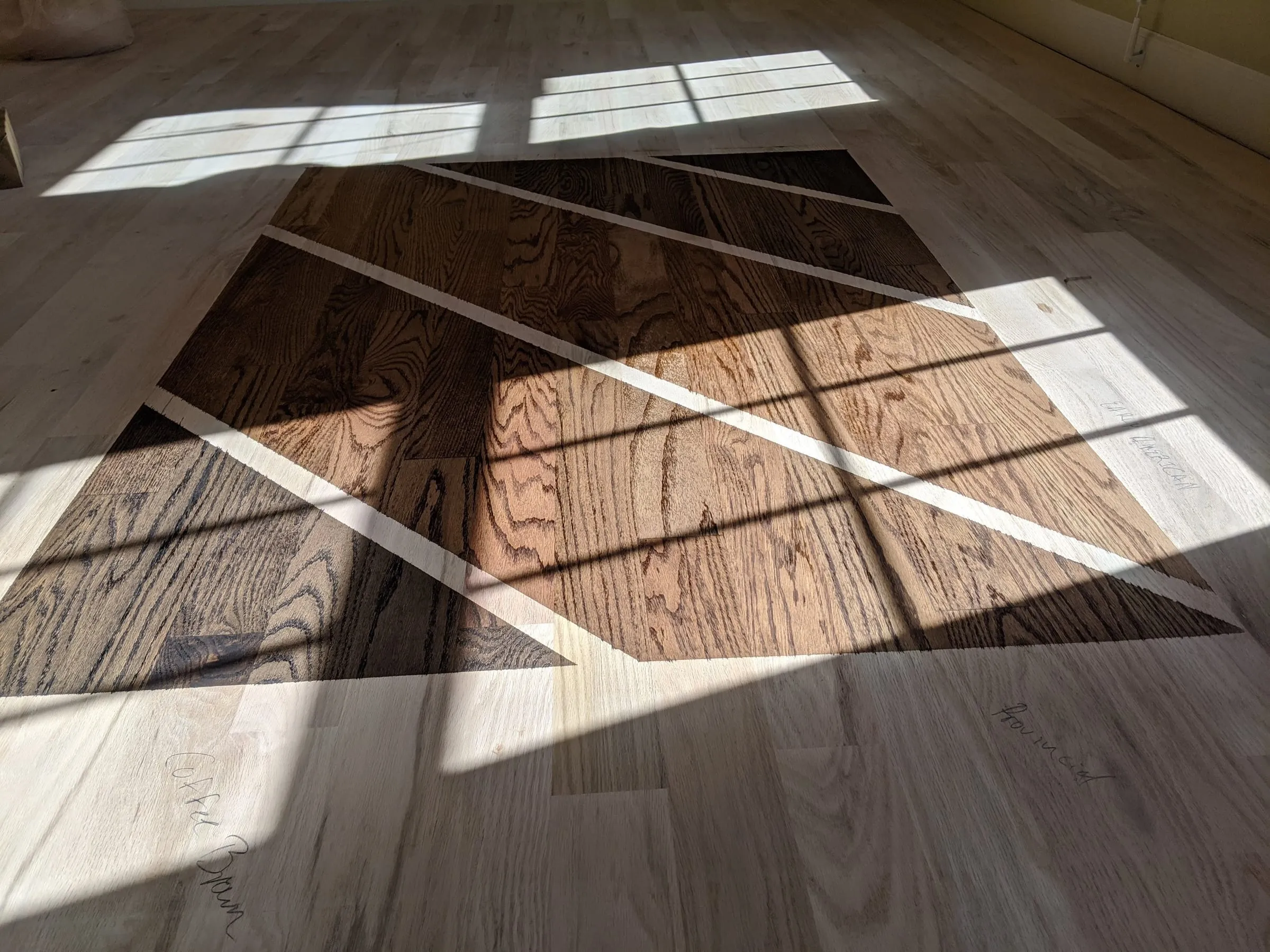 Close-up of a dark stain sample on a sunlit sanded oak floor