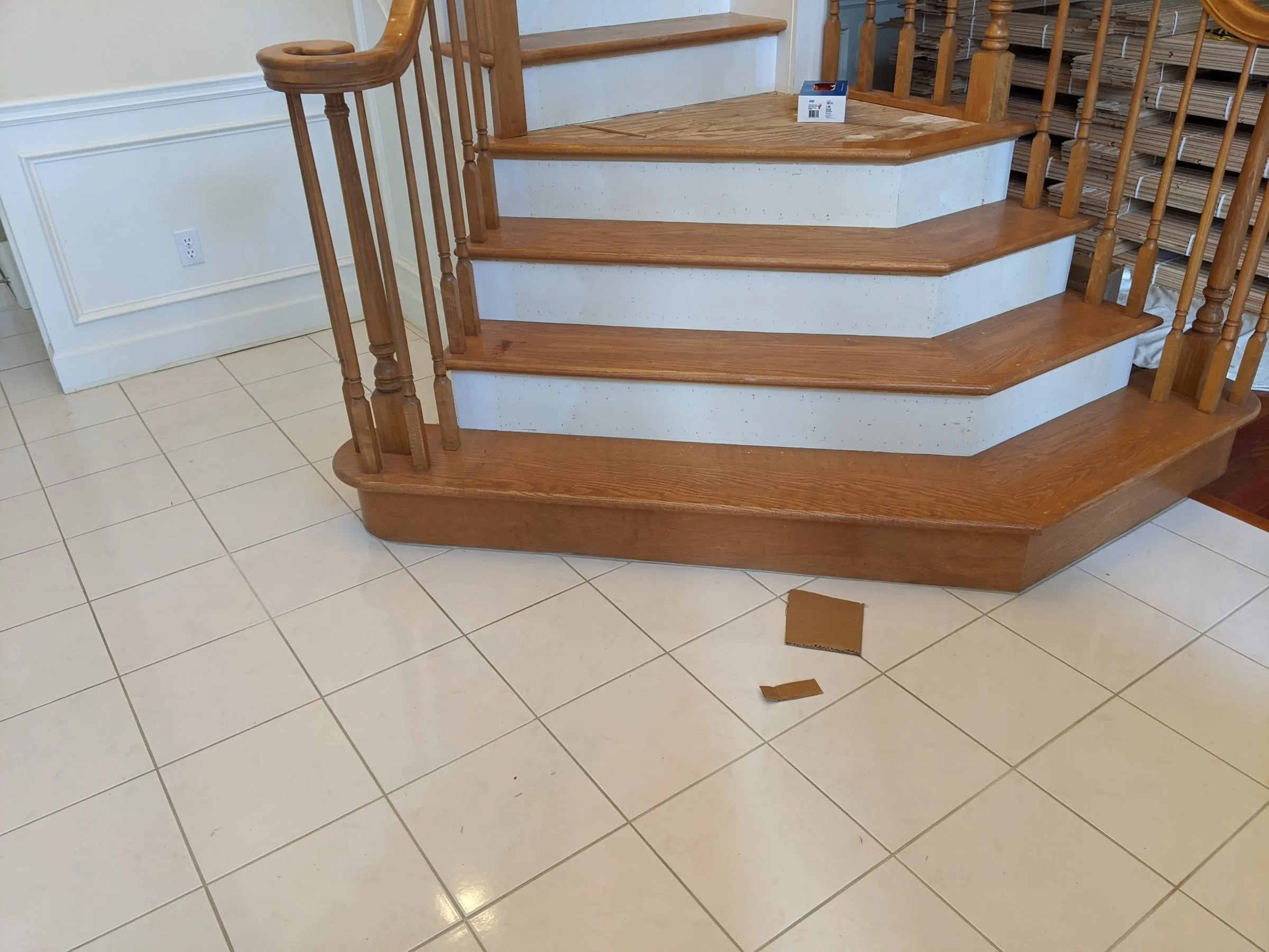 New oak treads and white risers on a curved staircase over a tile foyer