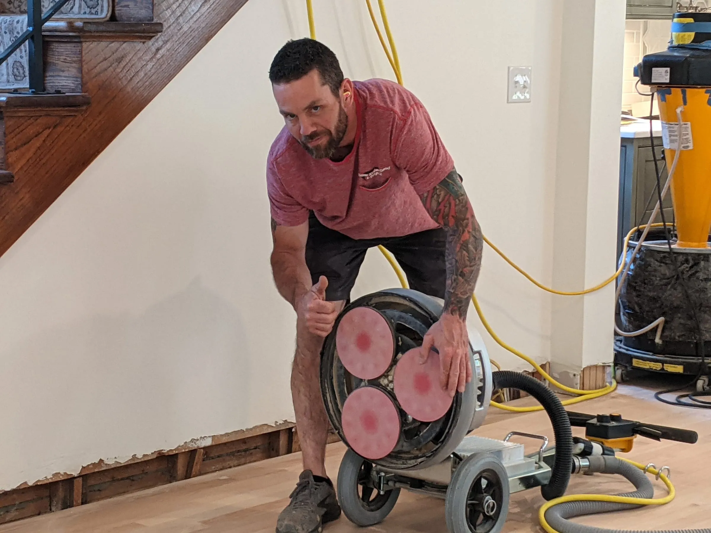 Floor technician holding up a multi-disc sanding machine